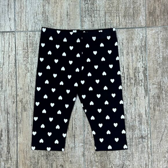 Flat lay of black leggings with white heart prints on wood background